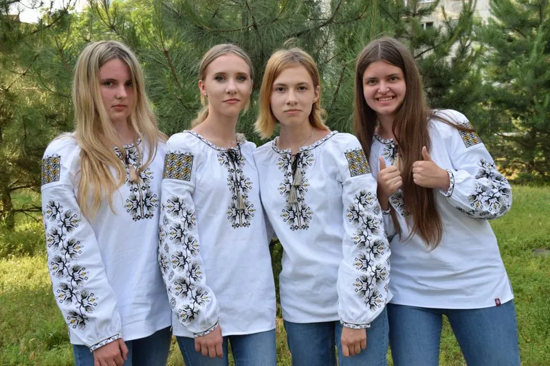 Four members of the team in embroidered shirts in front of pine trees